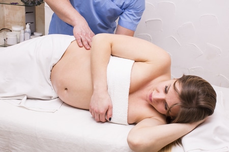 a massage therapist doing massage to a pregnant woman
