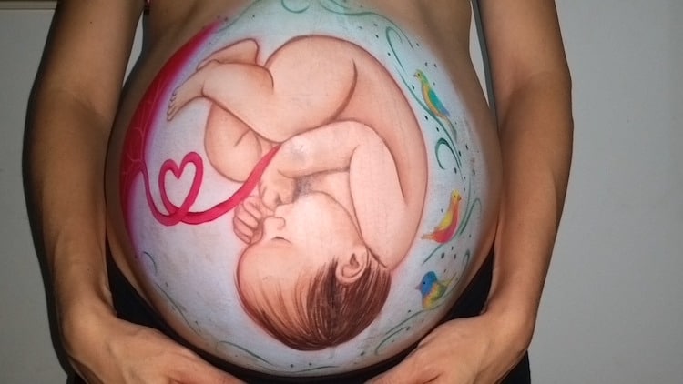 A pregnant woman's belly that has been painted to show the unborn baby inside. 