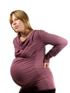 a pregnant woman holding her back because it hurts